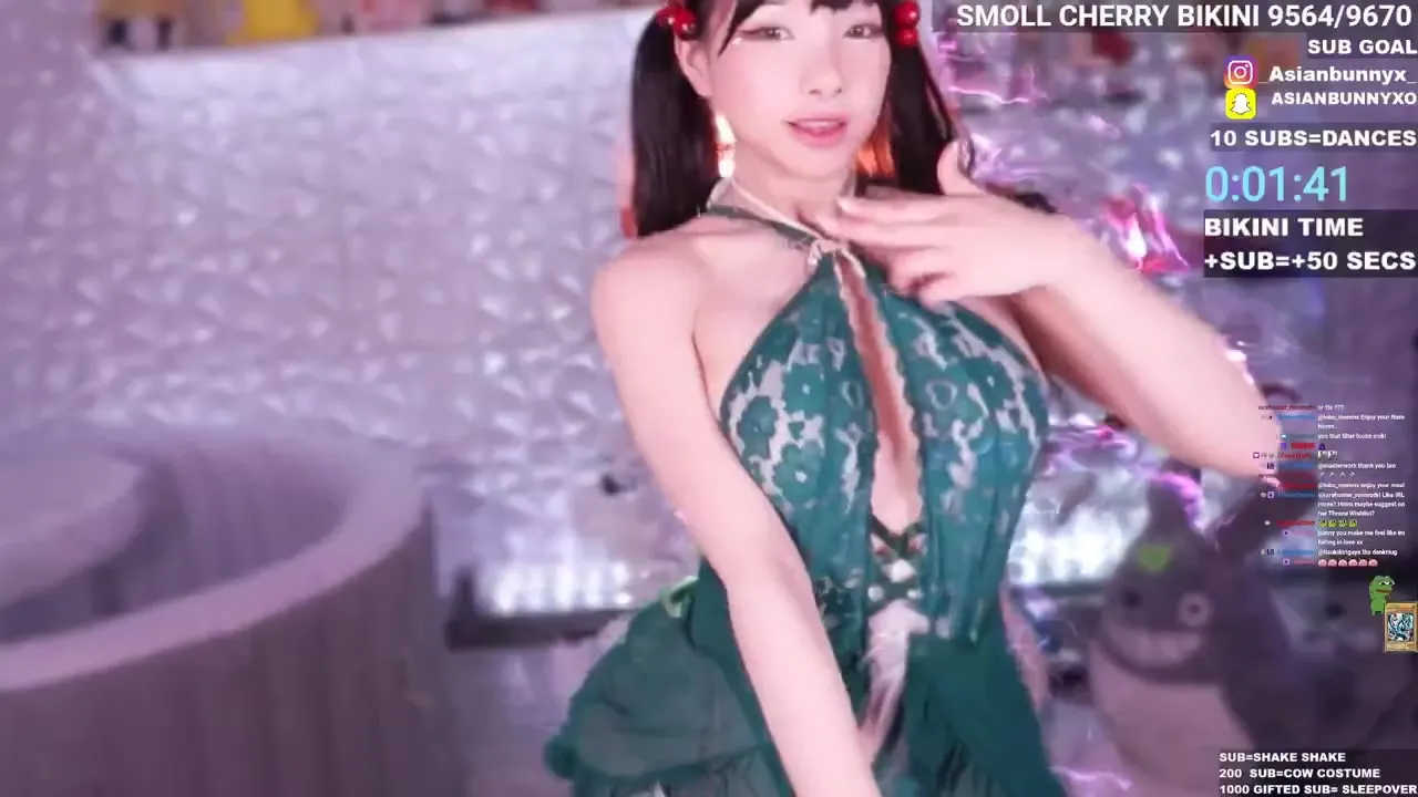 On her cam stream set, AsianBunnyx sways in a sheer green lace bikini, horny and hungry for tips