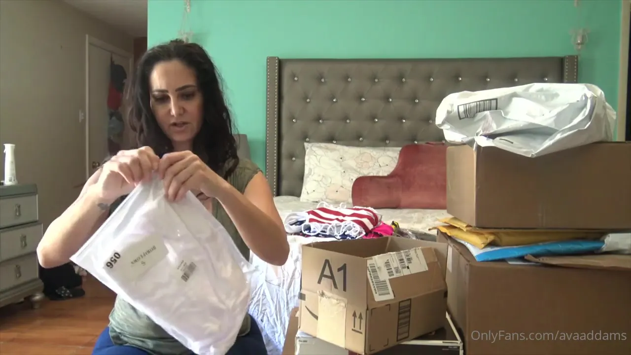 Ava Addams tears open a box of lingerie and toys, grinning like a horny little slut on the floor