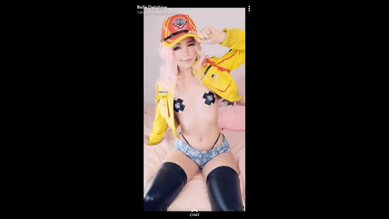 On a pink bed, Belle Delphine peels off her yellow jacket and flaunts her tits in pasties