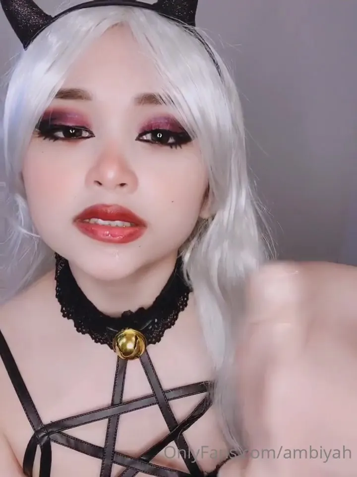 Stroking a glossy toy cock in white wig and devil horns, Mae parts her red lips