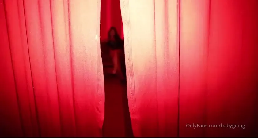 In the red-lit room, KatiesWorld grinds on the couch in latex, hips rolling