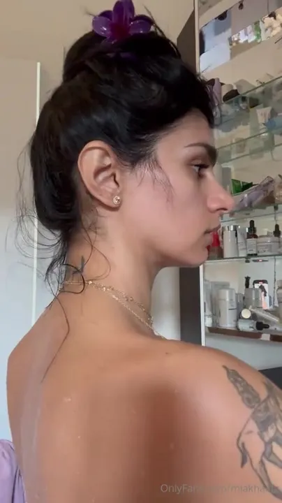 Buttoning up a white shirt, Mia Khalifa flashes her tits and tattooed back
