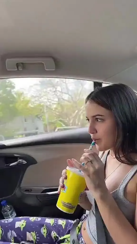 In patterned pants and a yellow-cup grin, Mikaela Testa sips and giggles at the pump