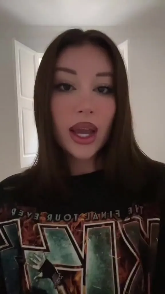 After work, Mikaelatesta chats in a black band tee in a hotel room