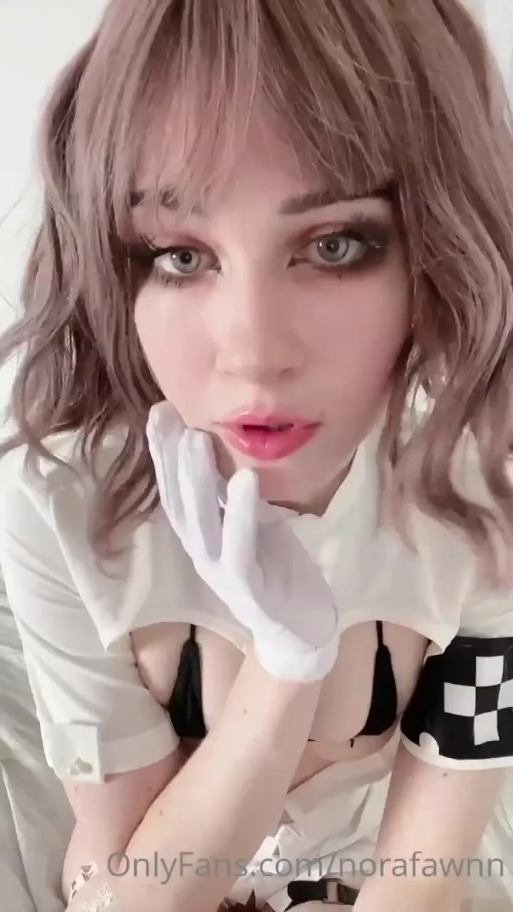 Posing in a nurse dress and gloves, Nora Fawn teases her curves on the sheets