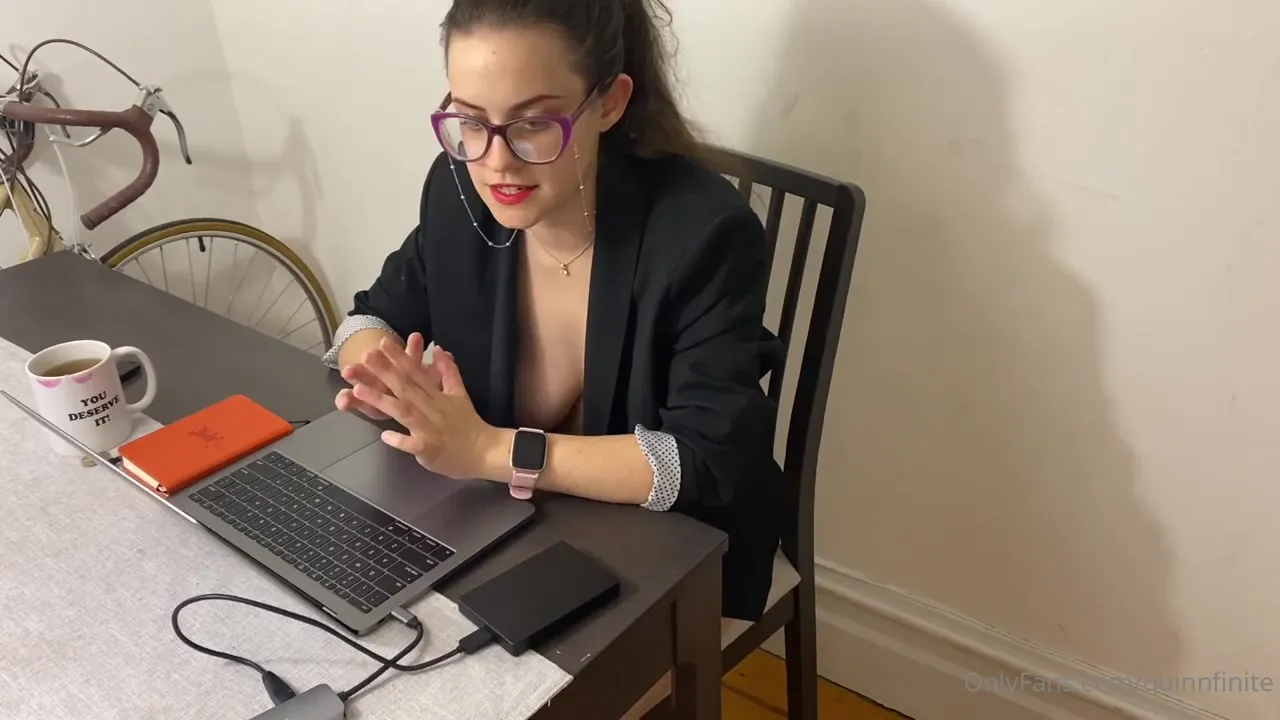 Leaning over her desk in a black blazer, Quinn Finite flashes a wicked grin and checks her watch