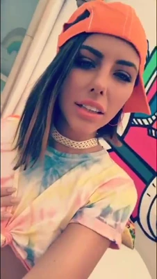 Adriana Chechik sips from a bottle in a tie-dye tee, hot and lazy