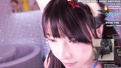 Lifting her orange skirt, AsianBunnyx bares her cheeks and peeks back