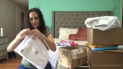 Ava Addams tears open a box of lingerie and toys, grinning like a horny little slut on the floor