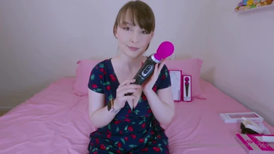 On a pink bed in a cherry-print dress, Belle Delphine ogles her new vibe and shoves it deep into her pussy