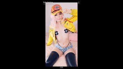 On a pink bed, Belle Delphine peels off her yellow jacket and flaunts her tits in pasties