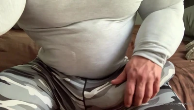 Cross-legged on the bed, Brogrowing strokes his cock through camo leggings and groans