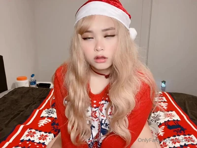 Mae in a Santa hat, sitting on the bed in a red Christmas sweater