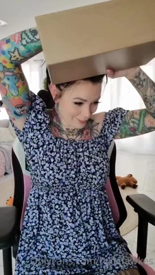 Ripping open a box in her navy dress while her ink flexes for the camera