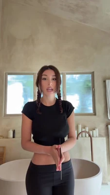 In a black crop top and leggings, Mikaela Testa shows off her skincare haul