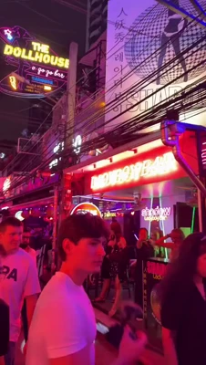 Mikaela Testa struts past glowing neon bar signs on a sleepy night street