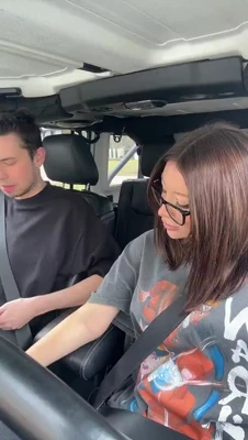 Mikaela Testa giggles in her glasses and graphic tee while a guy cracks up beside her