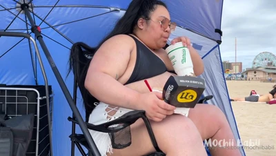 Mochii Babii eats loaded fries and churros by the ocean in her black bikini