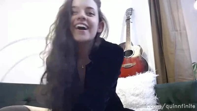 Tossing her long dark hair and laughing, Quinn Finite sprawls on the green couch in her black top