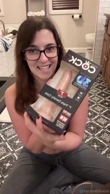 Sara Mei Kasai unboxes a huge flesh-colored dildo and grins on the bathroom floor