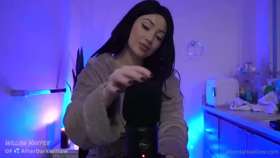 Willow Harper fiddles with a fuzzy mic cover in her blue-lit kitchen