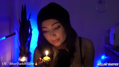 Studio after dark, Willow Harper in a black beanie blowing out her candle, lips grazing the mic